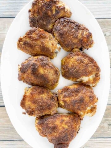 Baked chicken thighs on a white platter.
