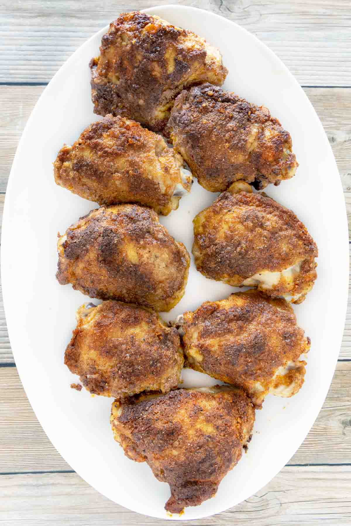 Baked chicken thighs on a white platter.