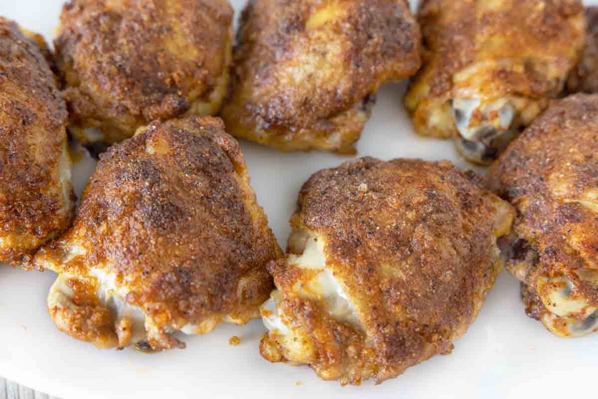 Baked chicken thighs on a white platter.