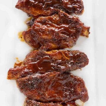 Barbecued country style pork ribs on a white platter.