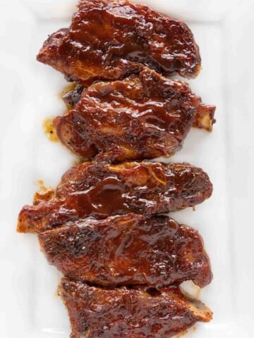 Barbecued country style pork ribs on a white platter.
