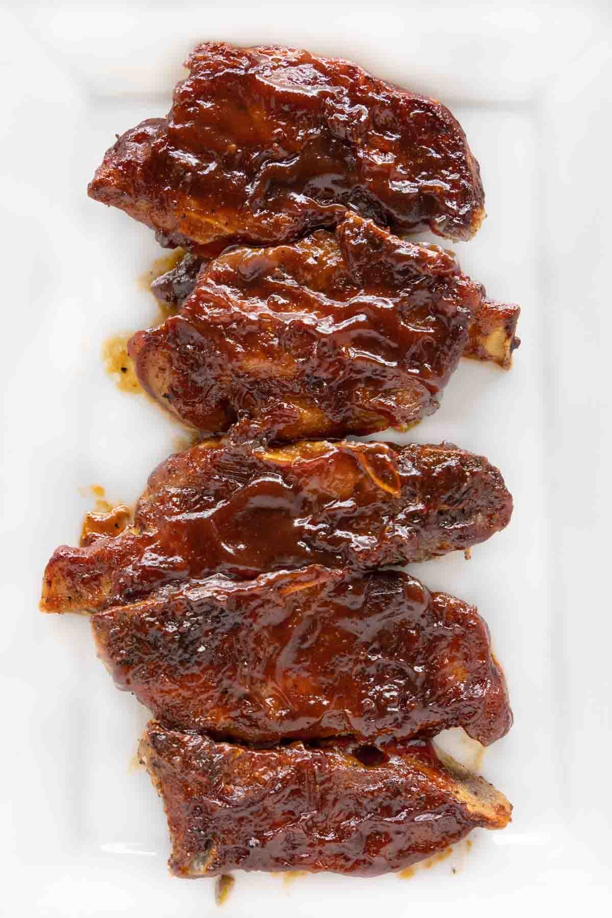 Barbecued country style pork ribs on a white platter.