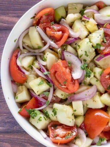 Cucumber tomato salad in a white bowl.