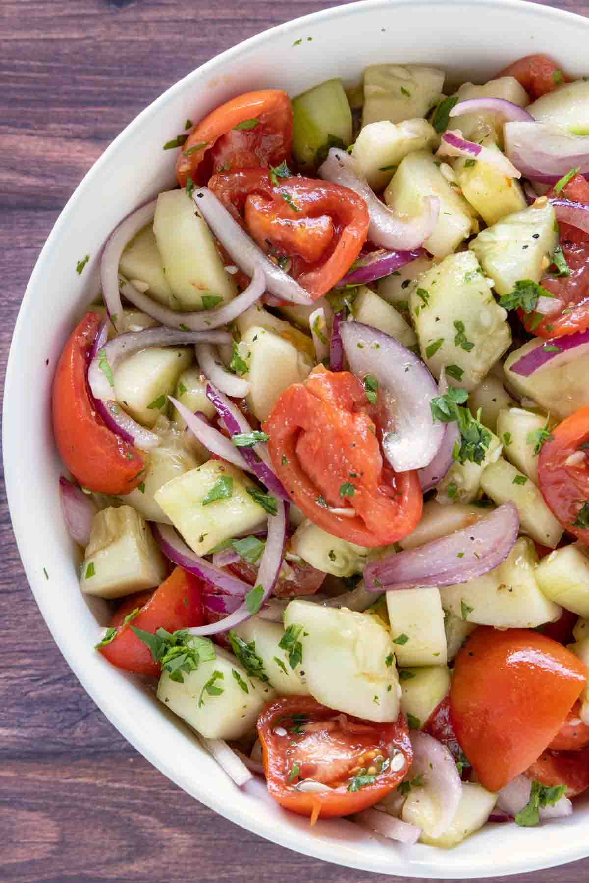 Cucumber tomato salad in a white bowl.