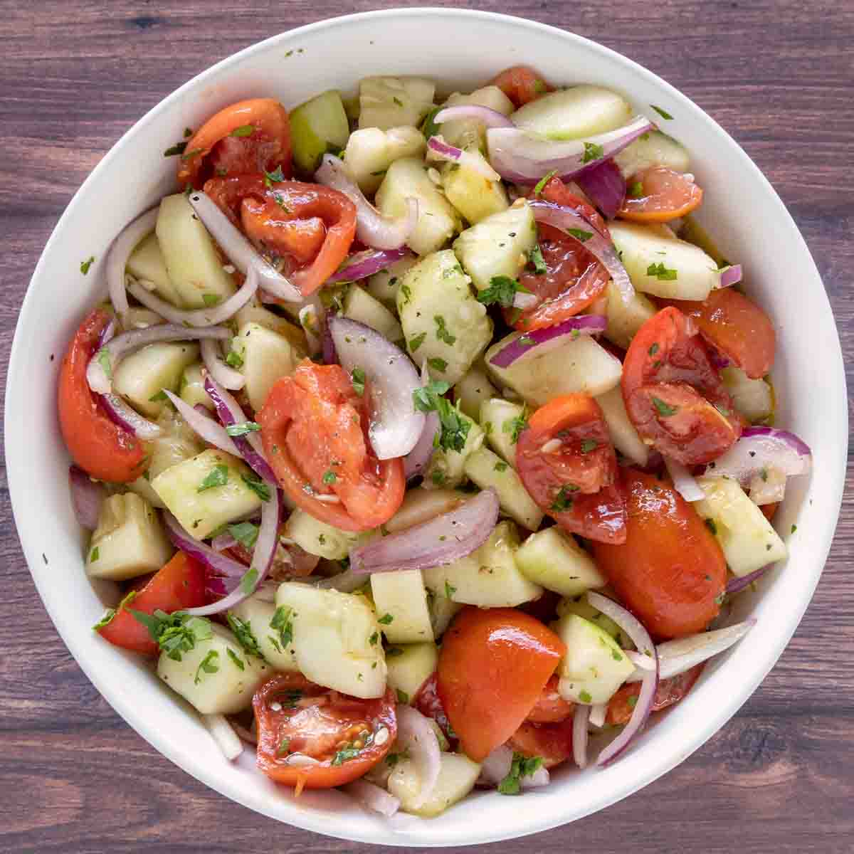 Cucumber tomato salad in a white bowl