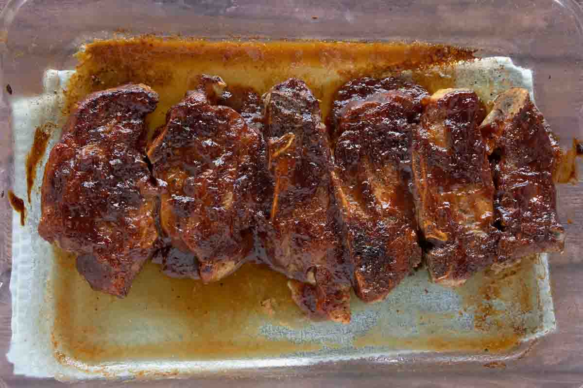 cooked ribs with barbecue sauce in a baking dish.