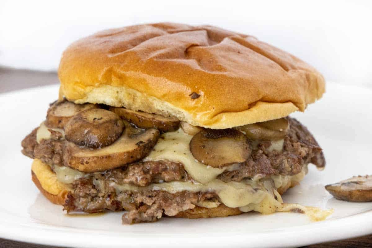 Mushroom Swiss smash burger on a white plate.