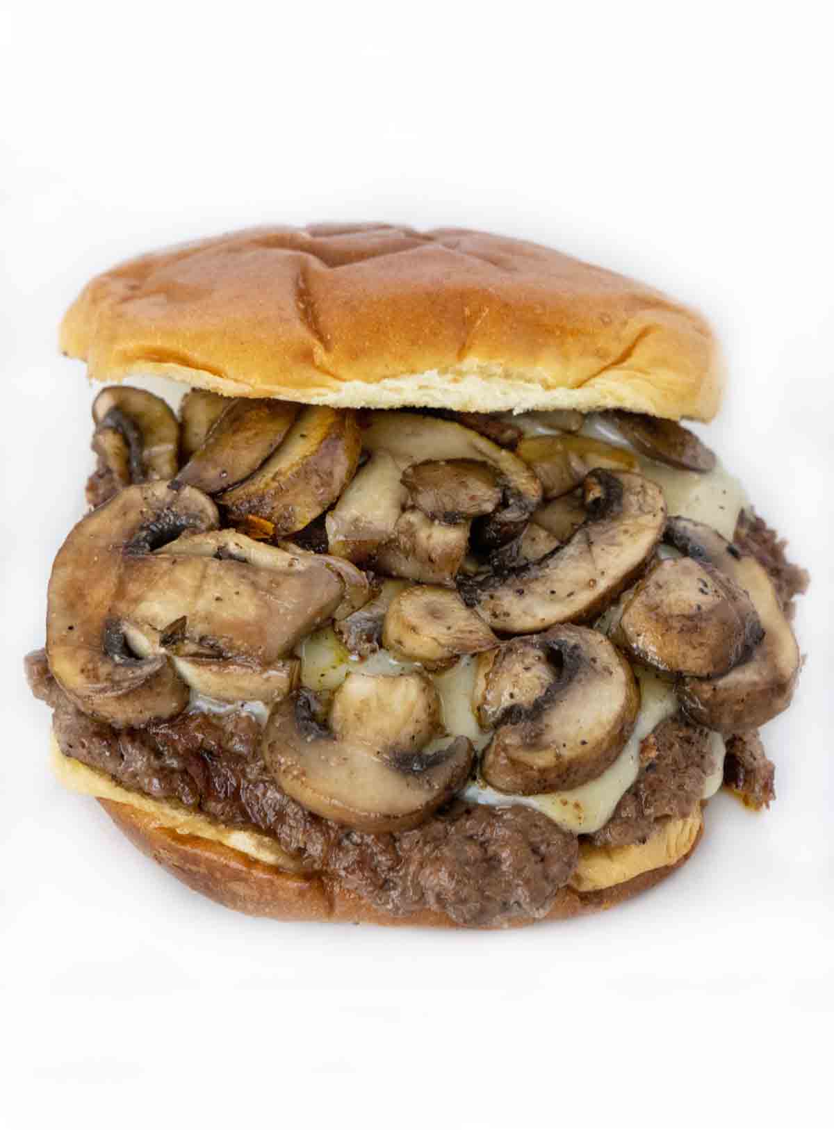 Mushroom Swiss smash burger on a white plate.