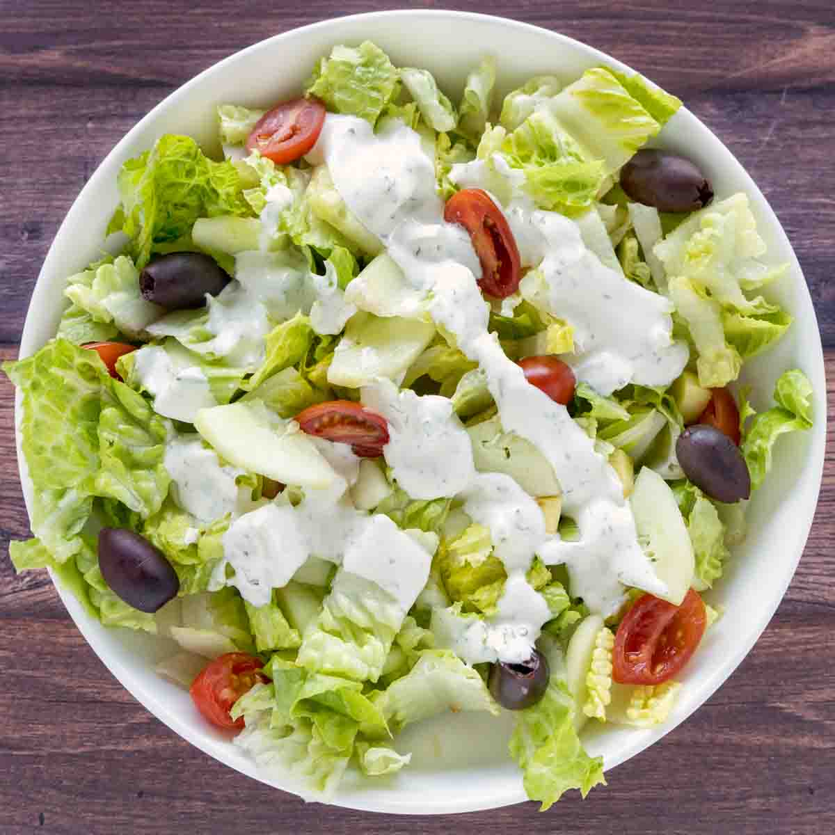Garden salad with dressing in a white bowl.