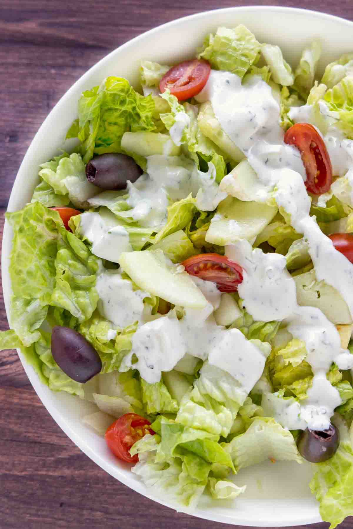 Garden salad with ranch dressing in a white bowl.