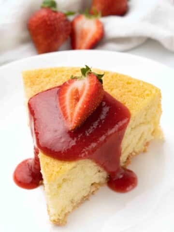 Slice of sponge cake with strawberry coulis on a white plate.