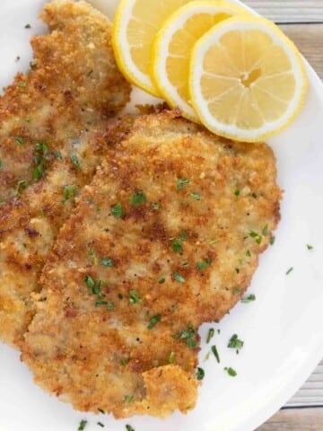 Wiener Schnitzel (veal schnitzel) on a white plate with lemon circles.