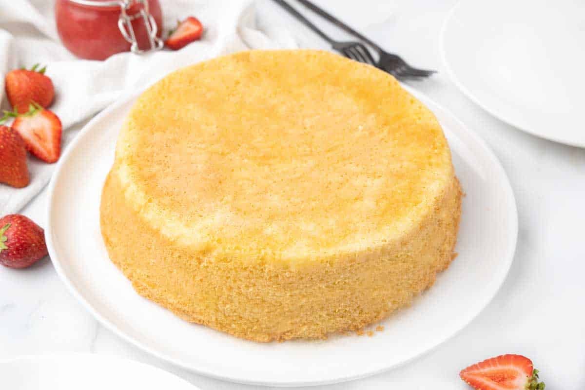 Whole sponge cake on white platter.