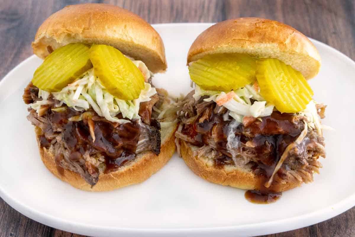 Smoked pulled pork sandwiches on a white platter.