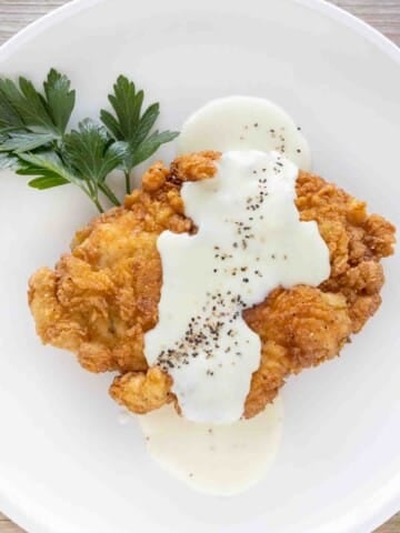 Chicken fried chicken with country gravy on a white plate.