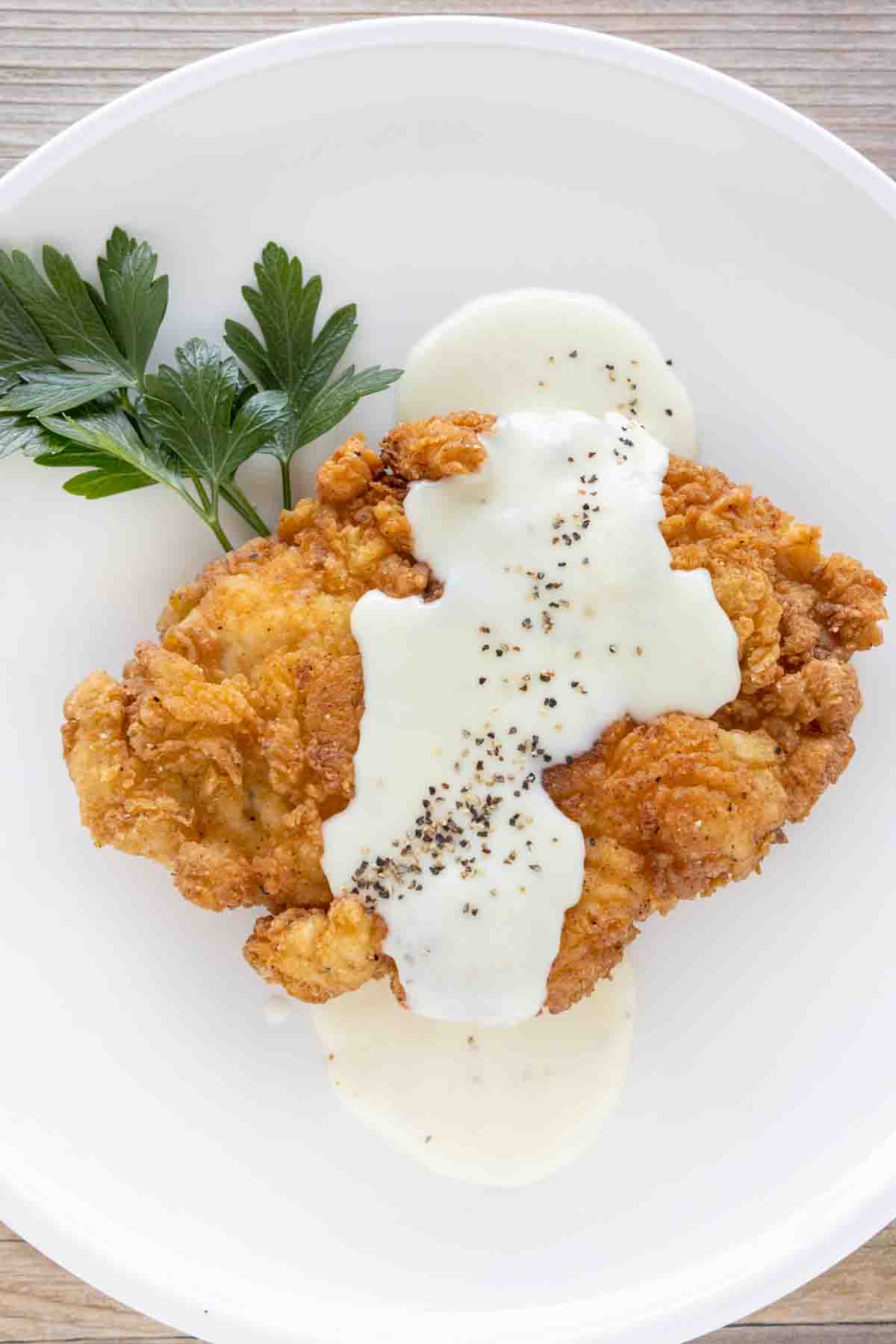 Chicken fried chicken with country gravy on a white plate.