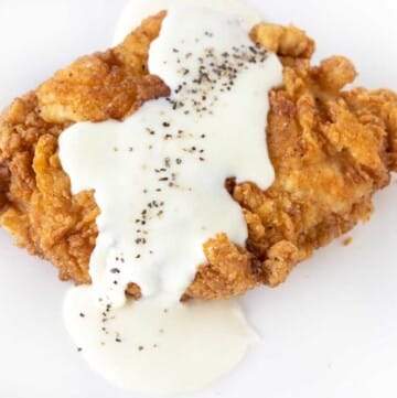 Chicken fried chicken with country gravy on a white plate.