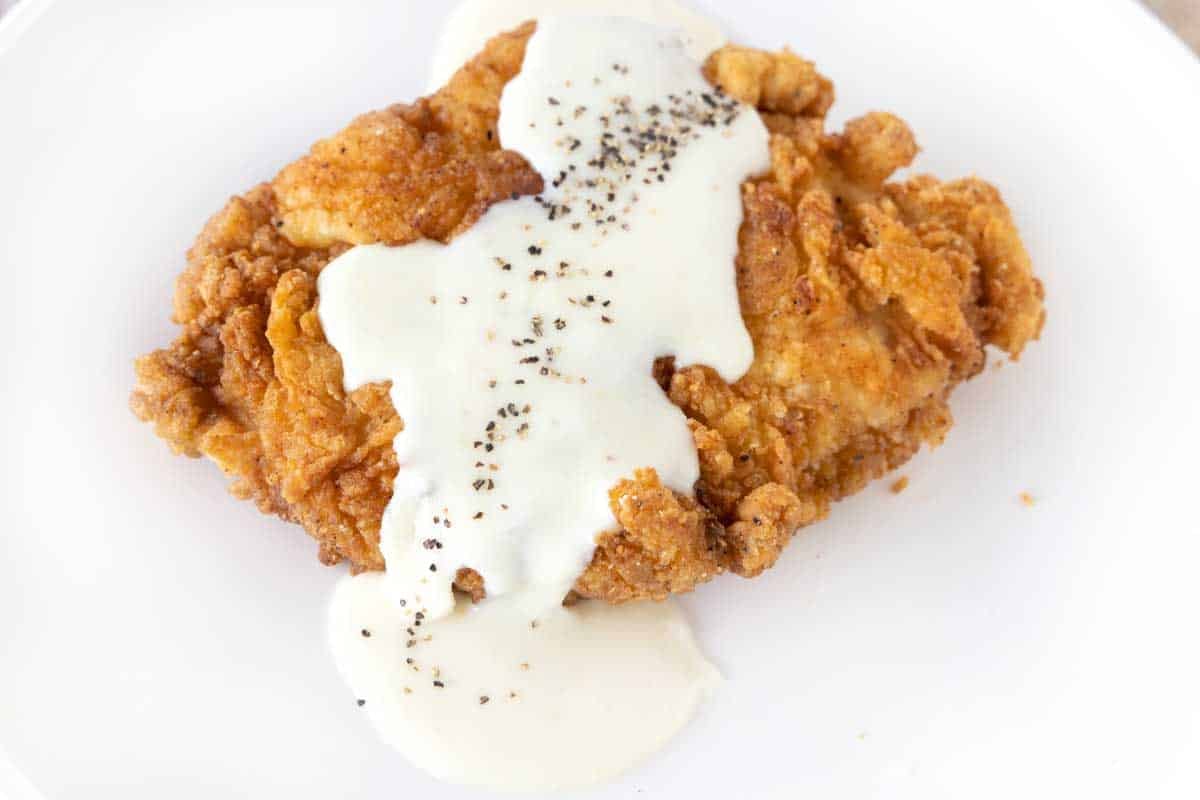 Chicken fried chicken with country gravy on a white plate.