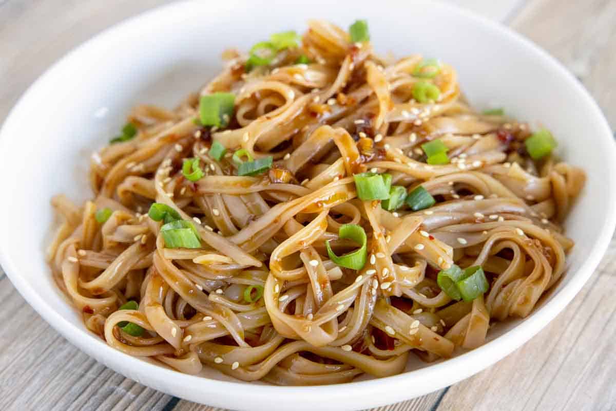 spicy chili garlic noodles in a white bowl.