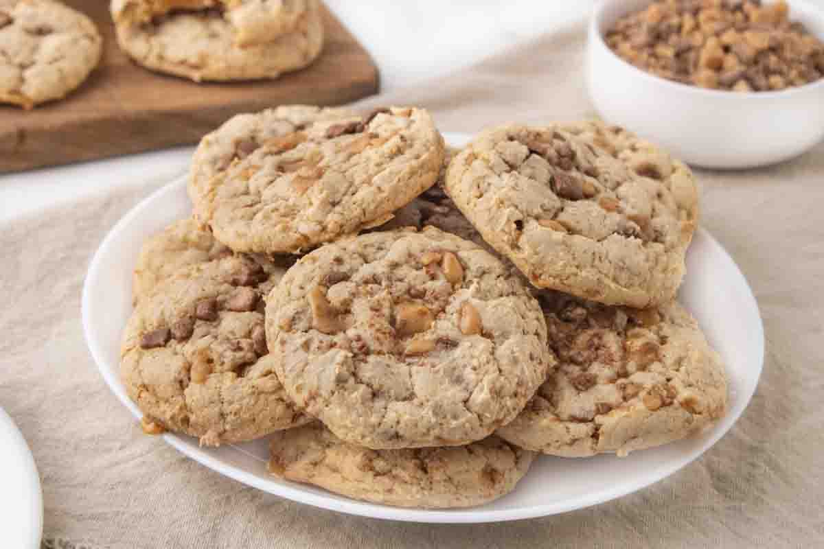 heath bar cookies stacked on a white plate.