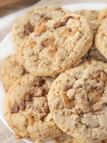 heath bar cookies stacked on a white plate.