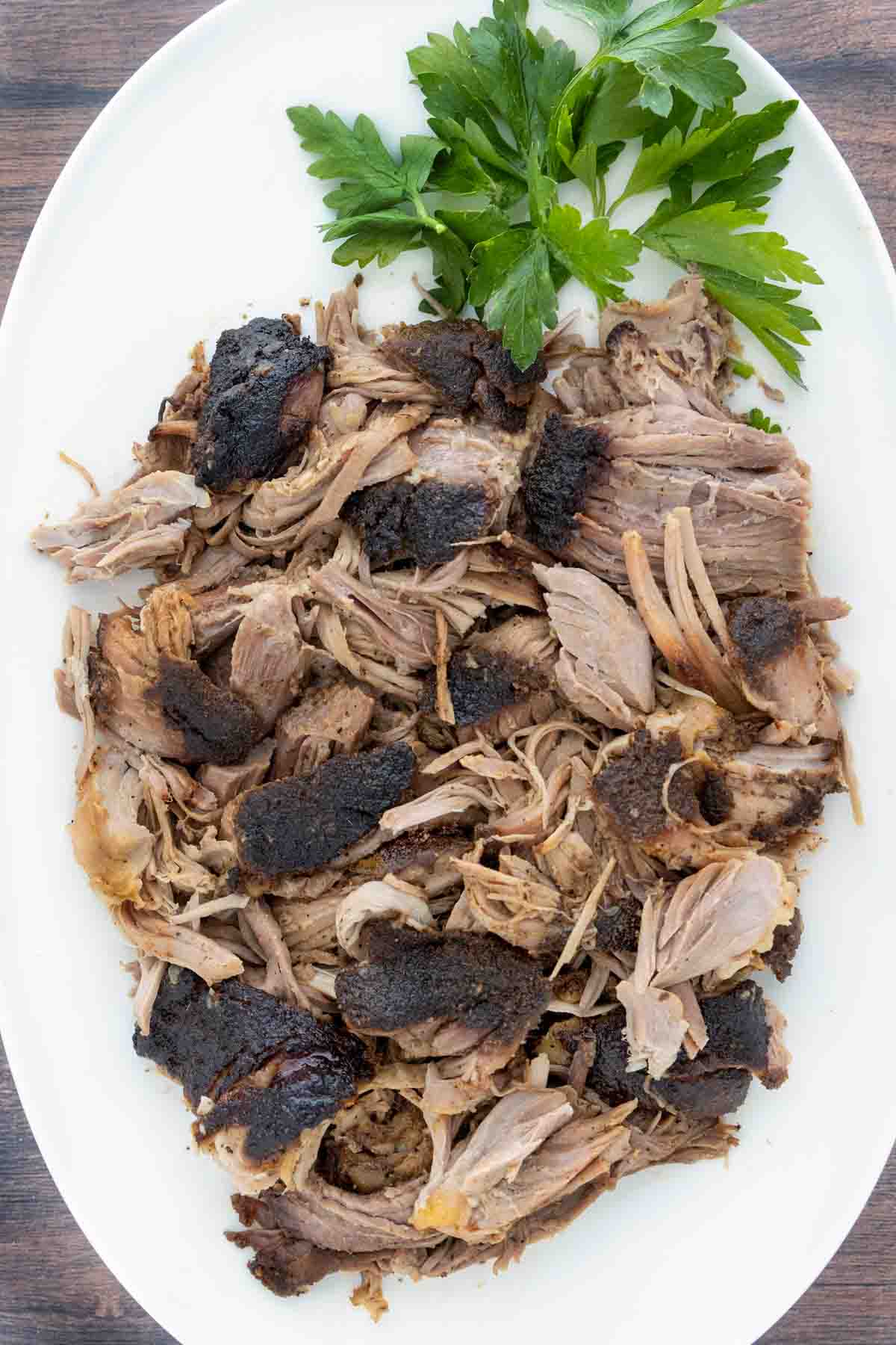 Smoked pulled pork butt on a white platter.