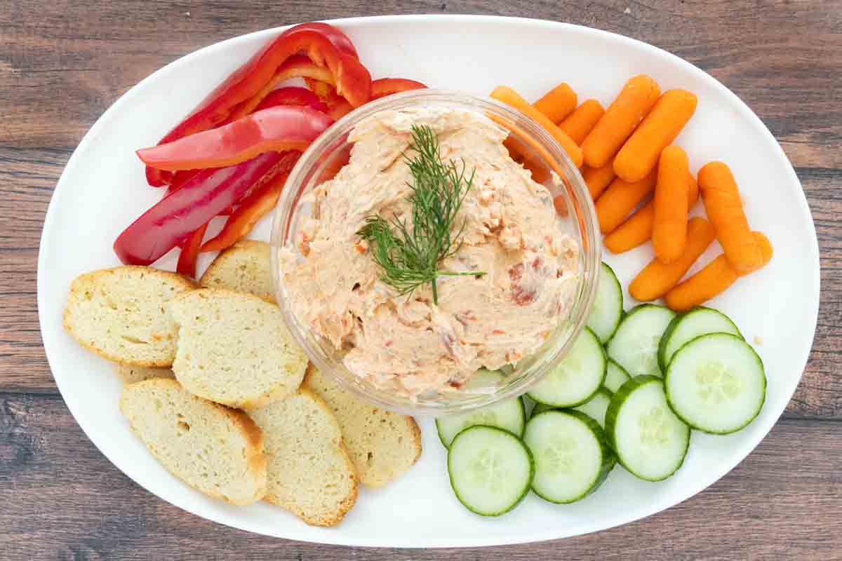 smoked salmon dip on a white platter with veggies and crackers.