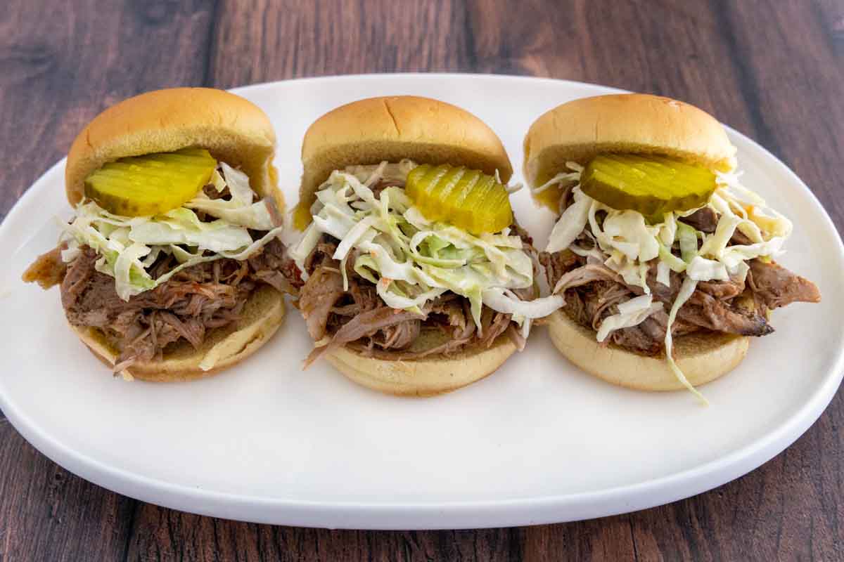Smoked pulled pork sliders on a white platter.