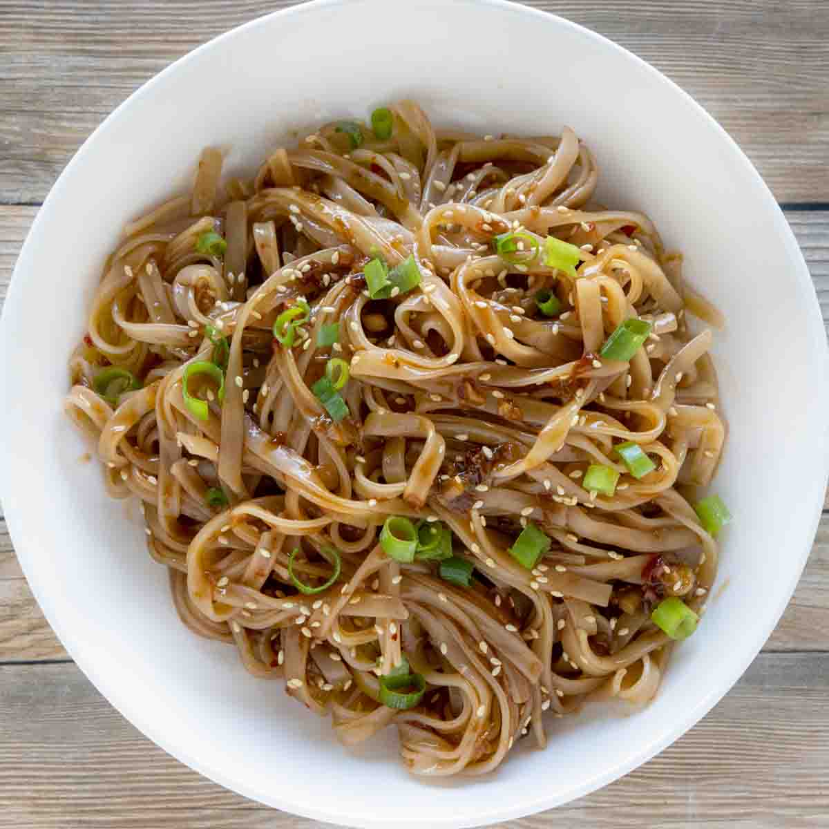 spicy chili garlic noodles in a white bowl.