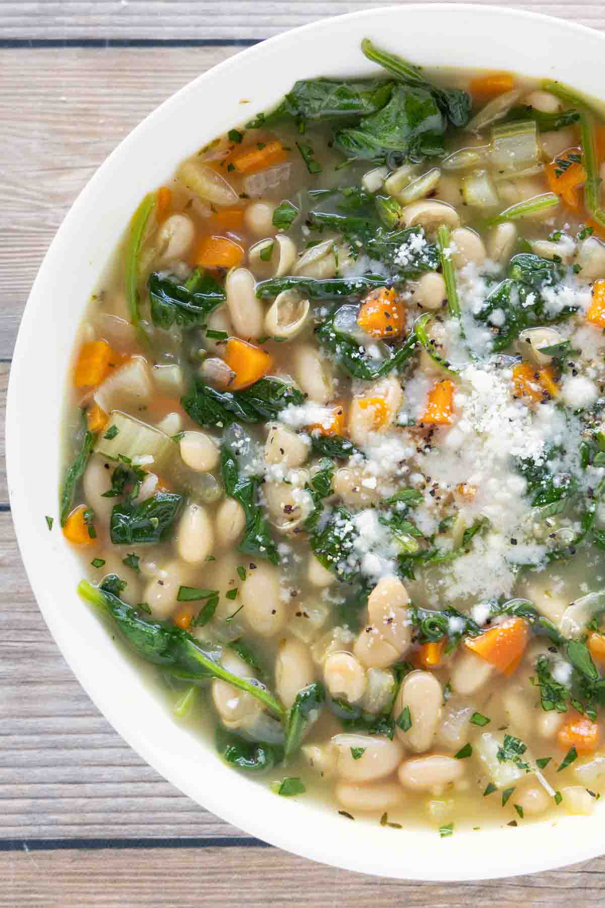 White bean soup with a sprinkle of parmesan cheese in a white bowl.