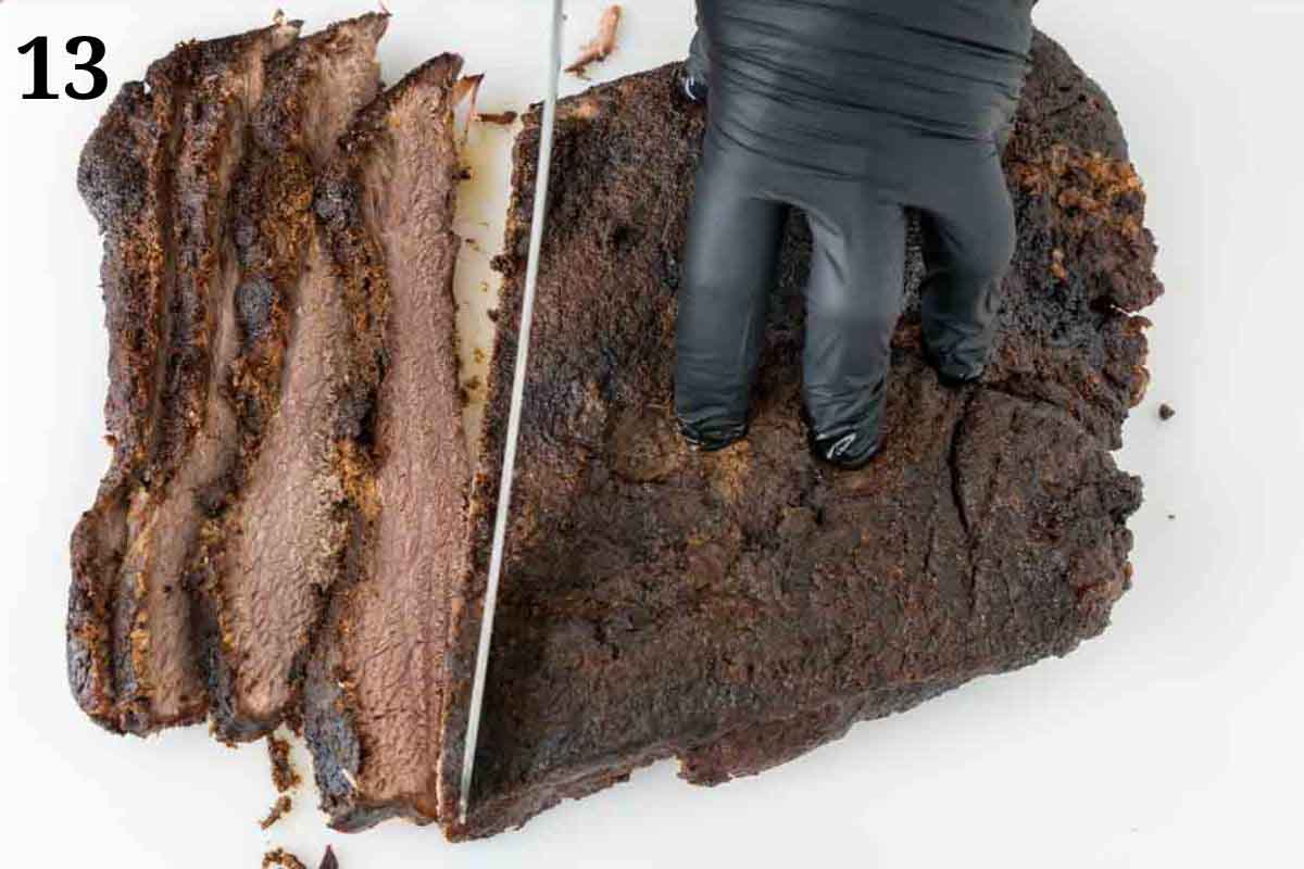 gloved hand holding smoked beef brisket while being sliced.