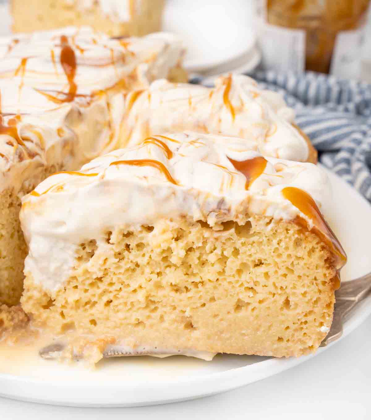 Slice of tres leches cake on a white plate.