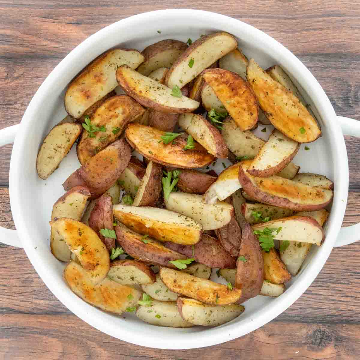 Oven roasted potato wedges in a white serving bowl.