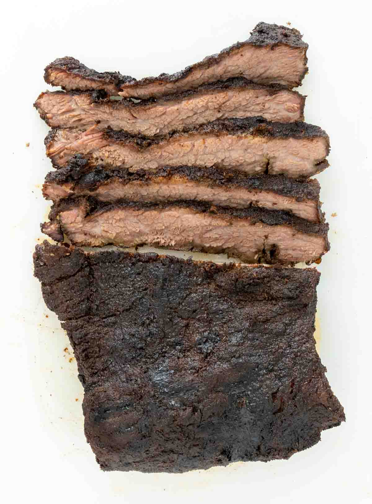 Sliced smoked beef brisket on a white platter.