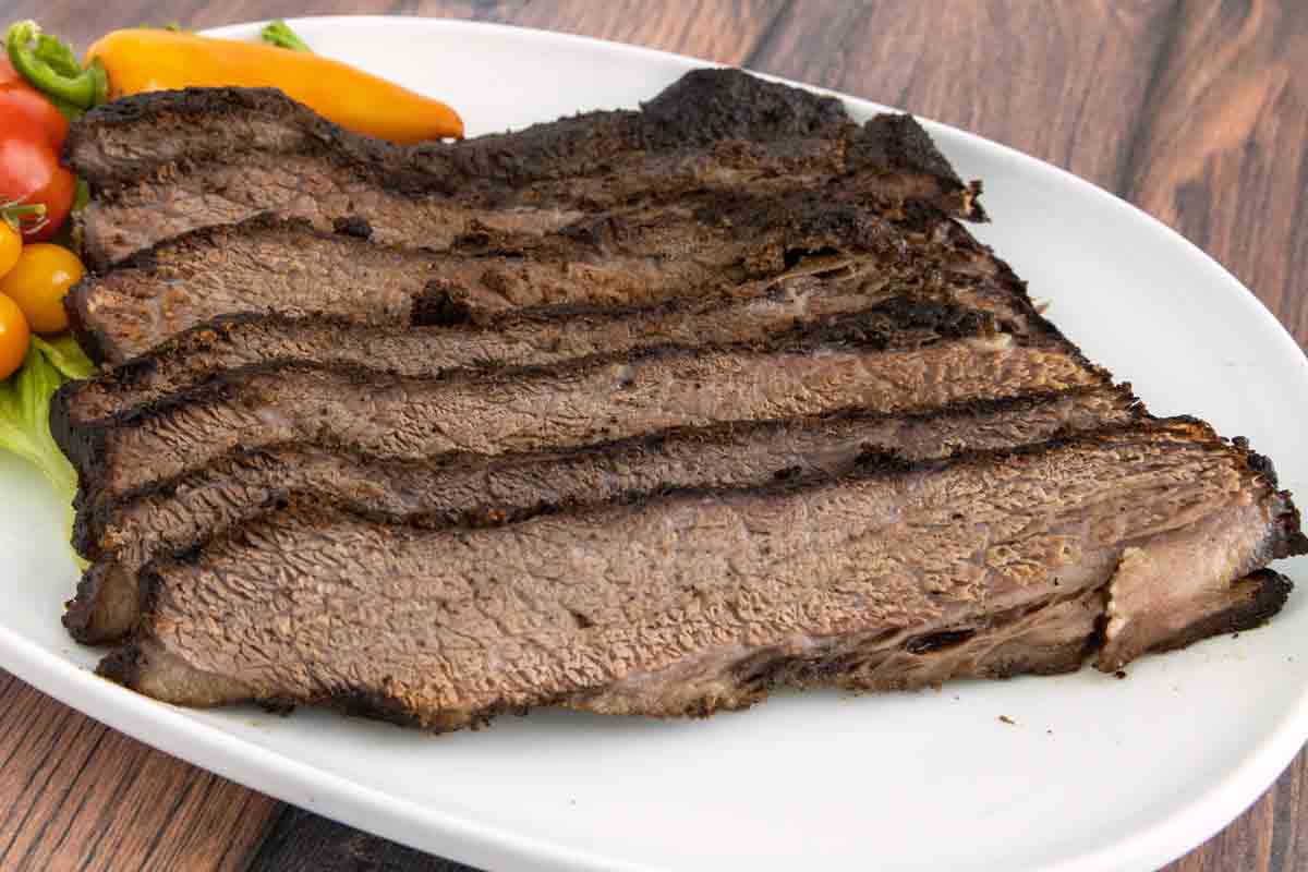 Sliced beef brisket on a white platter.