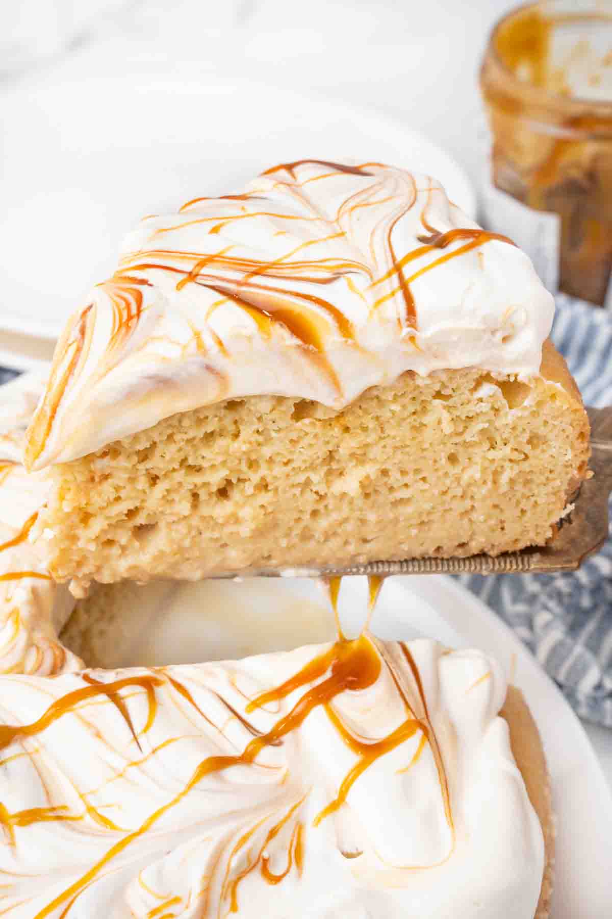 Slice of tres leches cake being taken out of whole cake.