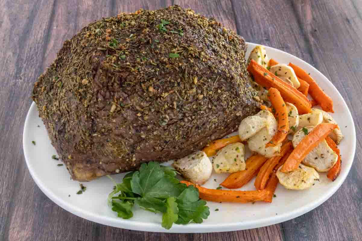 Garlic Herb Bottom Round on a white platter with roasted vegetables.