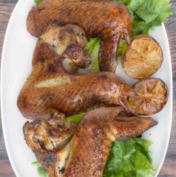 Smoked turkey wings on a white plate with greens.