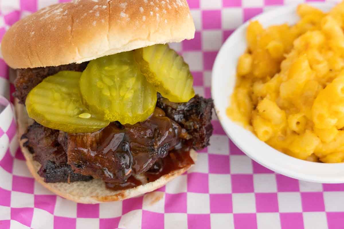 Barbecued smoked burnt ends on a bun with pickle chips.