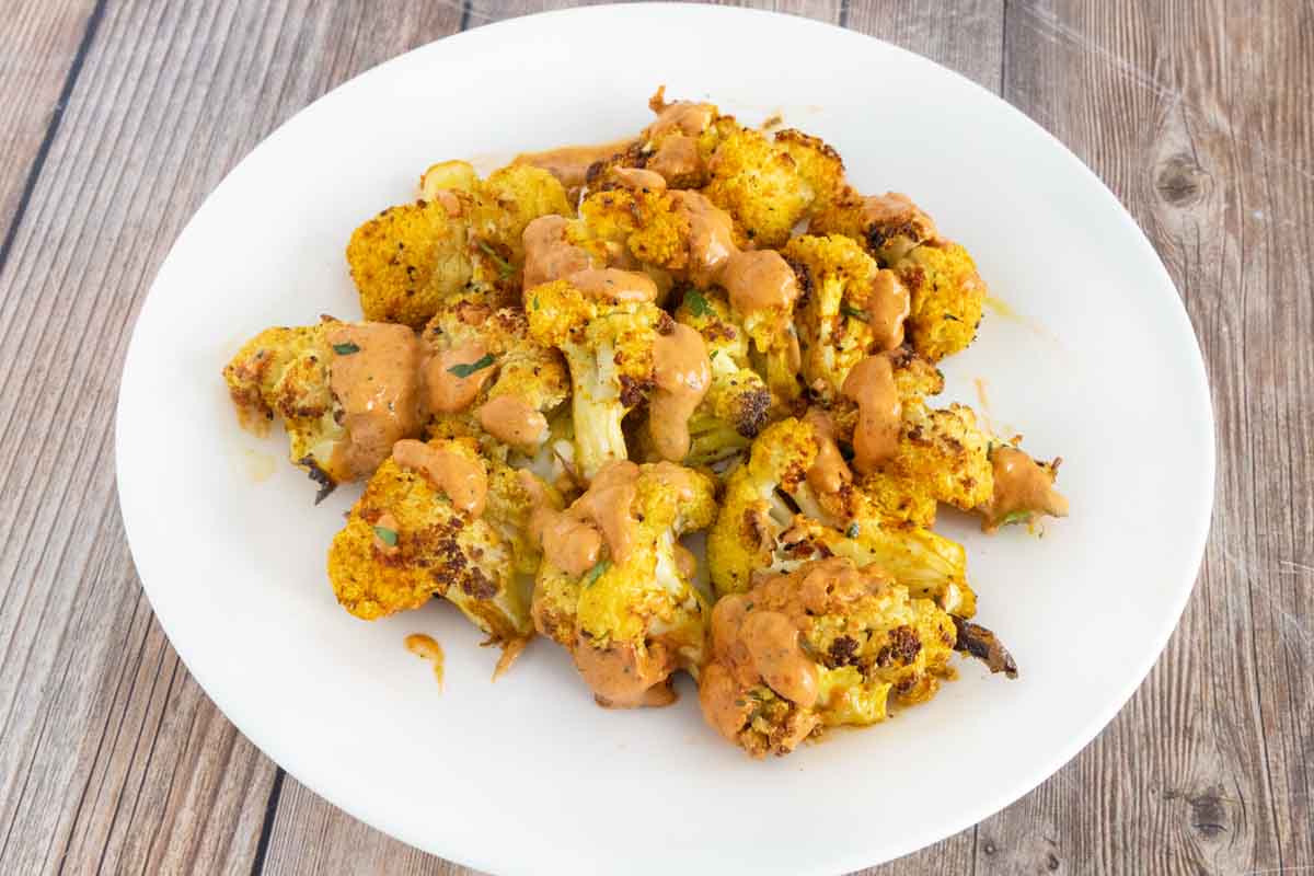 Roasted cauliflower with chipotle pepper sauce drizzled over top.
