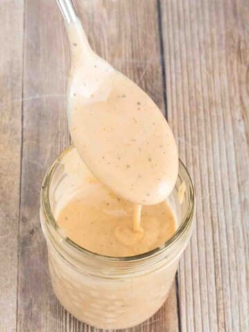 Chicken dipping sauce in a glass jar with a spoon coming out of it.