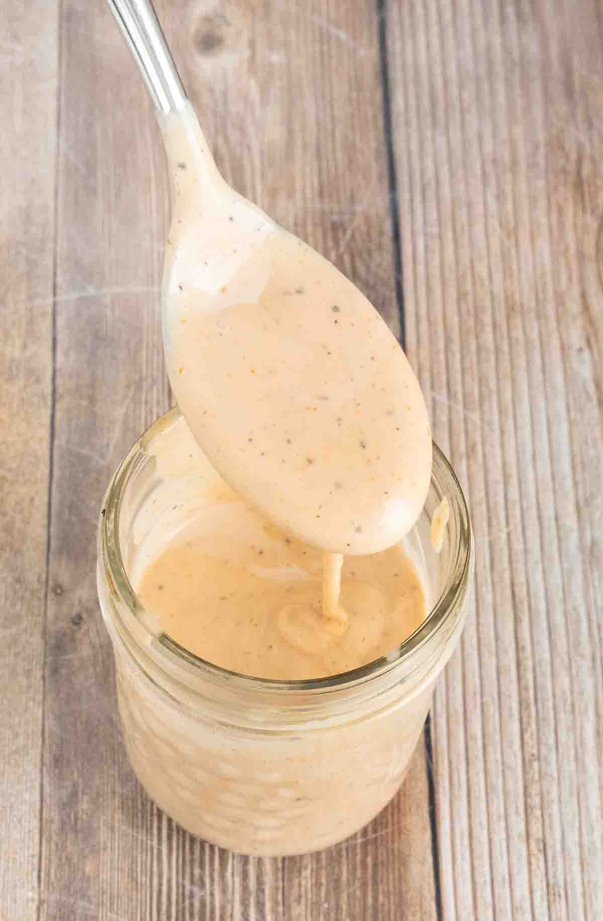 Chicken dipping sauce in a glass jar with a spoon coming out of it.