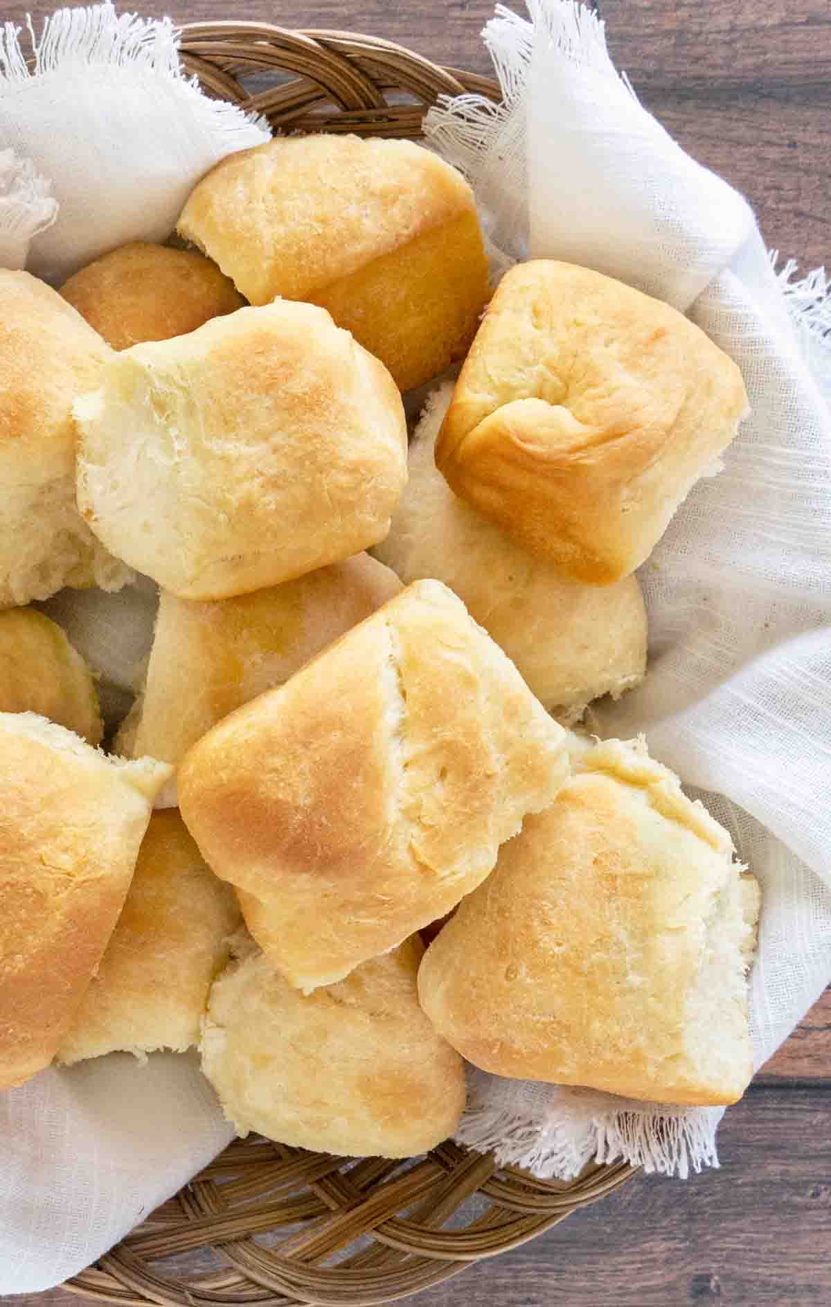 dinner rolls in basket with  white linen napkin.