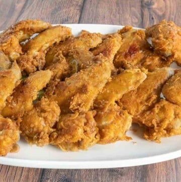 Fried chicken wings on a white platter.
