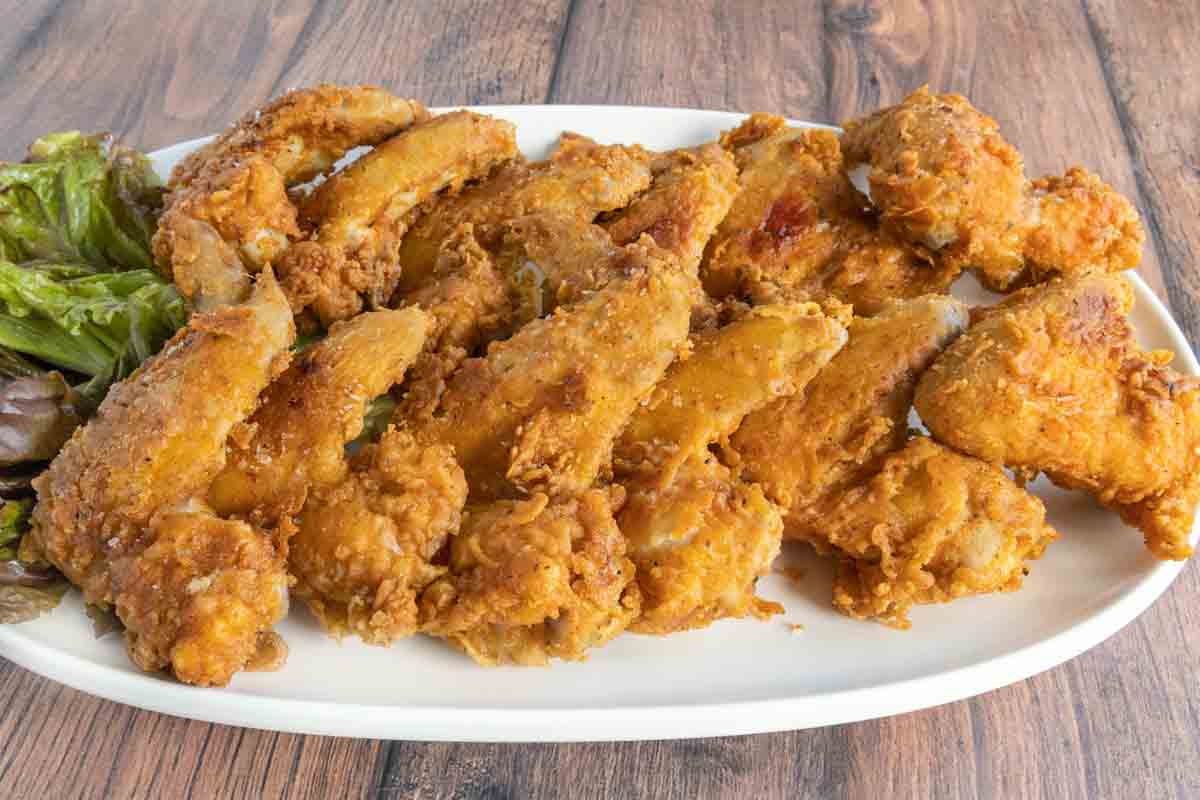 Fried chicken wings on a white platter.