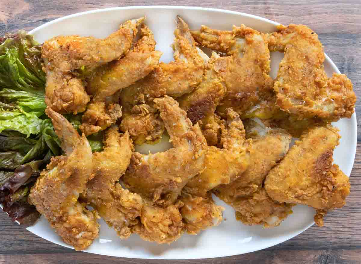 Fried chicken wings on a white platter.