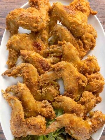 Fried chicken wings on a white platter.