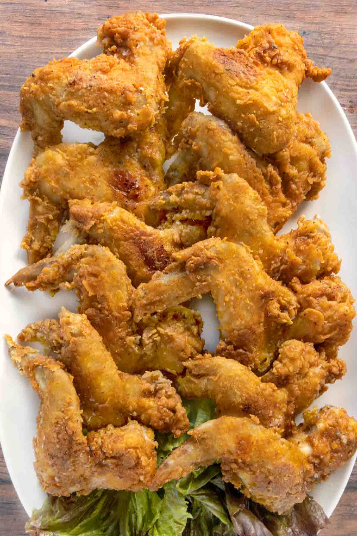 Fried chicken wings on a white platter.
