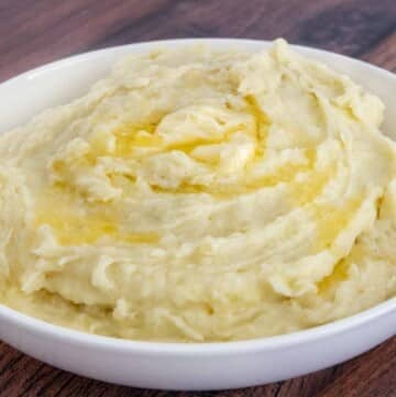 Mashed potatoes with butter melting on top in white bowl.