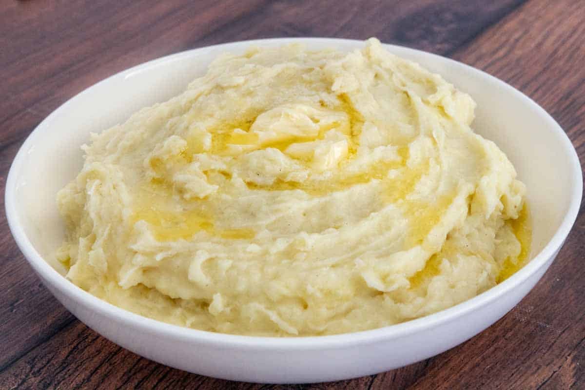 Mashed potatoes with butter melting on top in white bowl.